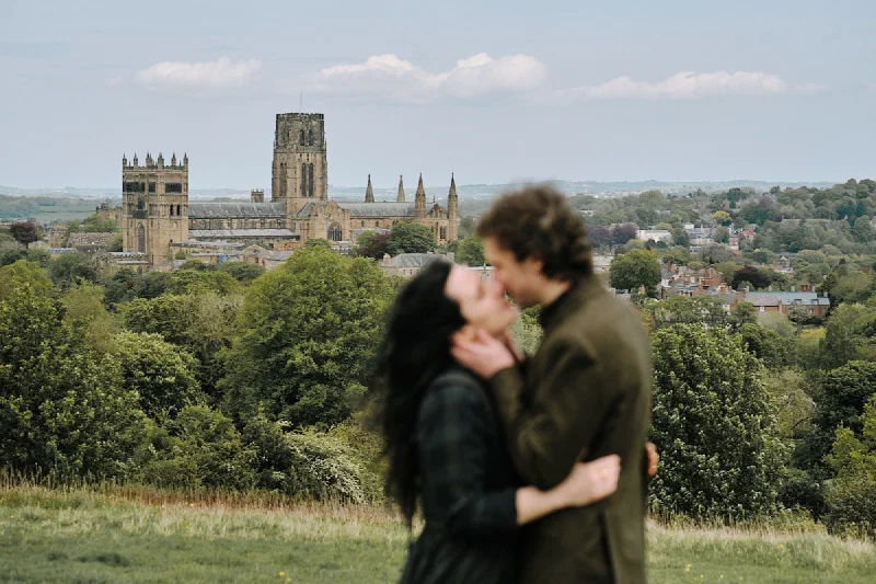 A newly engaged couple kissing with Durham Cathedral behind them