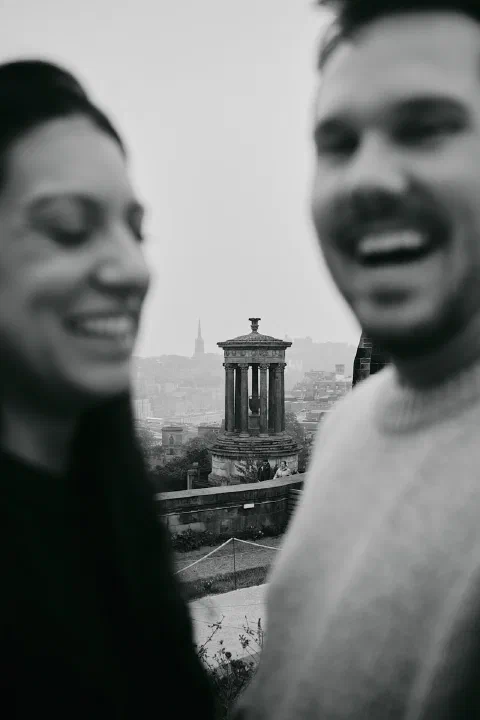 Black and white photograph of a smiling couple framing the Dugald Stewart Monument on Calton Hill