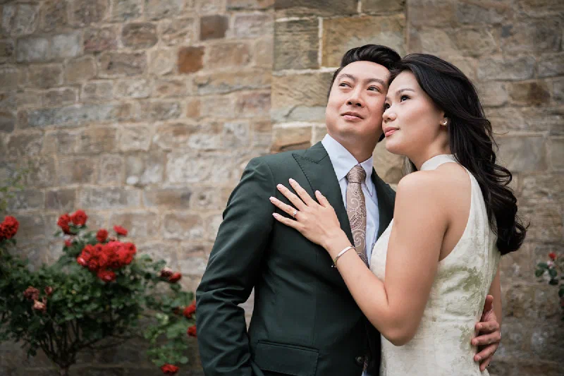 Newly engaged couple embracing beside a historic stone wall